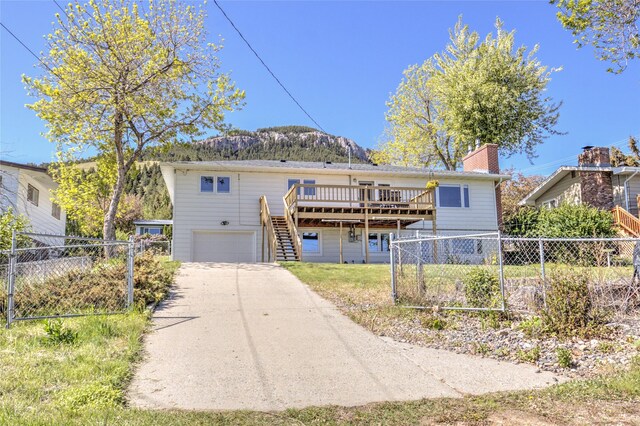 1320 Flowerree St, Helena, MT 59601 - back of house with stairway, a deck with mountain view, a garage, a chimney, and concrete driveway