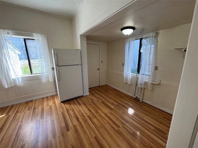 108 Meany St, Plains, MT 59859 - unfurnished dining area with light wood-style floors, a textured ceiling, baseboards, and crown molding