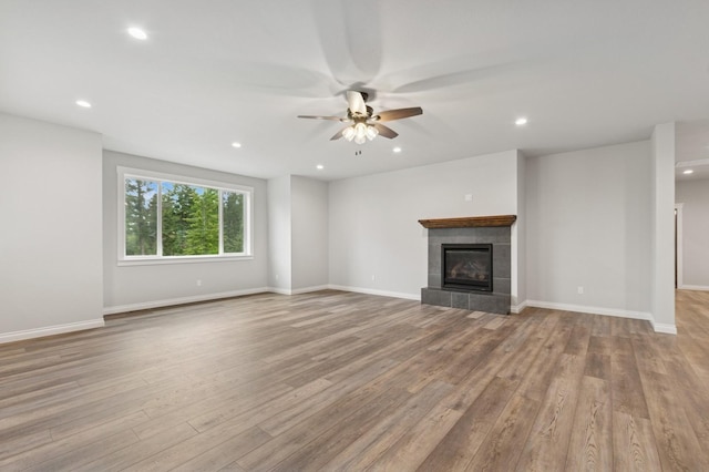 323 Skookum Rd, Lakeside, MT 59922 - unfurnished living room with ceiling fan, wood finished floors, recessed lighting, a tiled fireplace, and baseboards