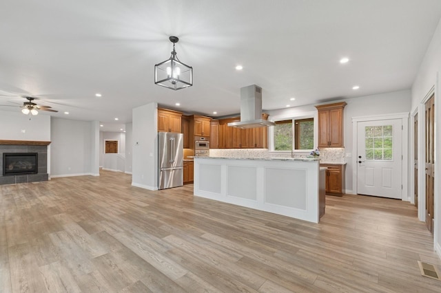 323 Skookum Rd, Lakeside, MT 59922 - kitchen featuring appliances with stainless steel finishes, island exhaust hood, open floor plan, brown cabinets, and recessed lighting