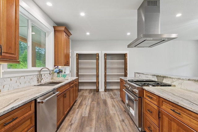 323 Skookum Rd, Lakeside, MT 59922 - kitchen featuring island exhaust hood, appliances with stainless steel finishes, a sink, light wood finished floors, and light stone countertops