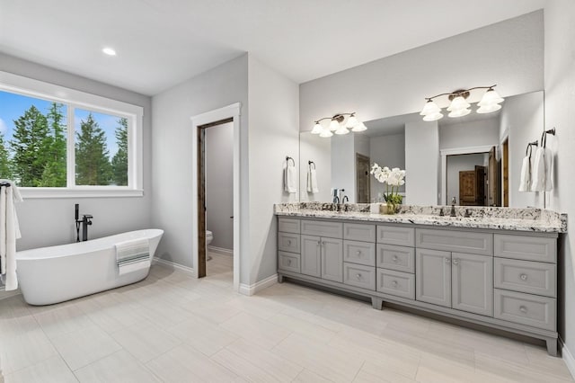 323 Skookum Rd, Lakeside, MT 59922 - full bathroom featuring double vanity, a freestanding tub, toilet, and baseboards
