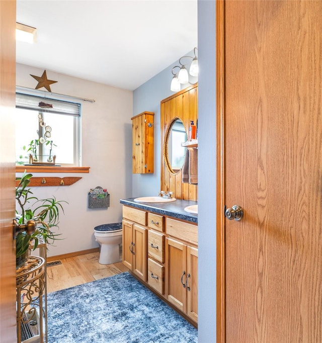 158 Parkside Dr, Kalispell, MT 59901 - bathroom featuring double vanity, wood finished floors, toilet, and baseboards