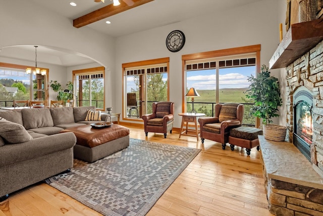 36665 Highland Ct, Polson, MT 59860 - living room with a fireplace, light wood-style floors, arched walkways, beamed ceiling, and a chandelier