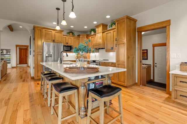 36665 Highland Ct, Polson, MT 59860 - kitchen with stainless steel appliances, a sink, arched walkways, light countertops, and light wood-type flooring