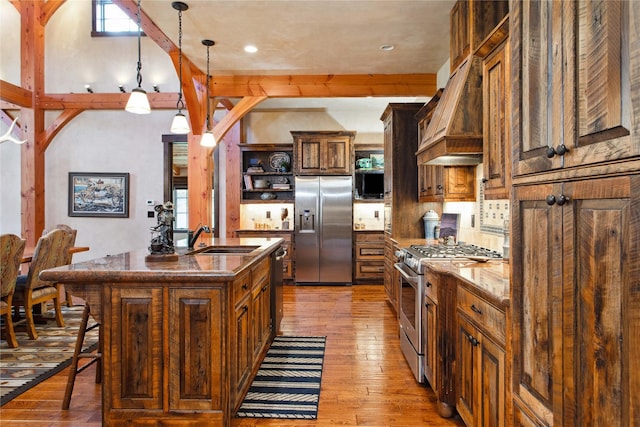 380 Haskill Basin Rd, Whitefish, MT 59937 - kitchen with appliances with stainless steel finishes, open shelves, light wood-type flooring, a kitchen bar, and a kitchen island with sink