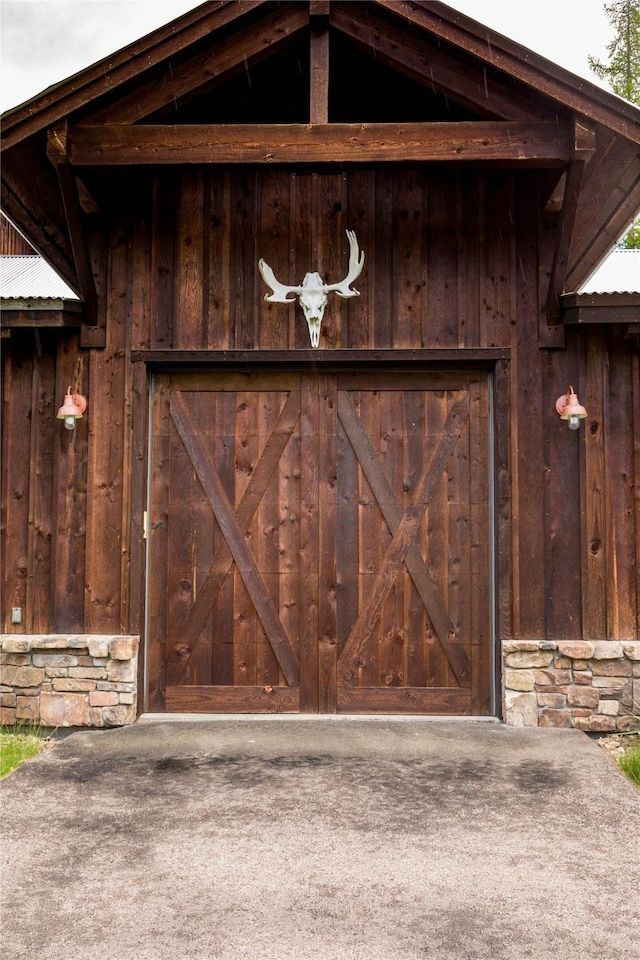 380 Haskill Basin Rd, Whitefish, MT 59937 - property entrance featuring stone siding, a garage, and board and batten siding