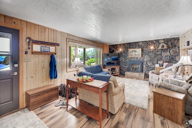 1502 Hauser Blvd, Helena, MT 59601 - living area featuring a textured ceiling, wooden walls, a stone fireplace, and wood finished floors