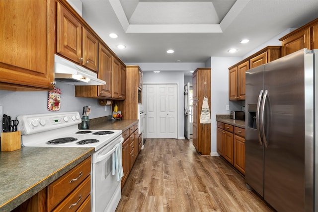 100 Rimini Rd, Lakeside, MT 59922 - kitchen with stainless steel fridge, white range with electric stovetop, under cabinet range hood, dark countertops, and brown cabinetry