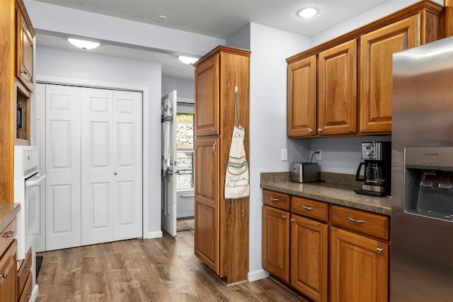 100 Rimini Rd, Lakeside, MT 59922 - kitchen with stainless steel refrigerator with ice dispenser, brown cabinetry, dark countertops, wood finished floors, and recessed lighting