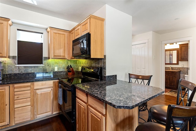 1 Kootenai Ave Unit 17, Polson, MT 59860 - kitchen featuring black appliances, a breakfast bar, dark wood-type flooring, and decorative backsplash