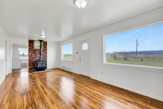 1680 W River Rd, Deer Lodge, MT 59722 - unfurnished living room with a baseboard radiator, a wood stove, a baseboard heating unit, and wood finished floors