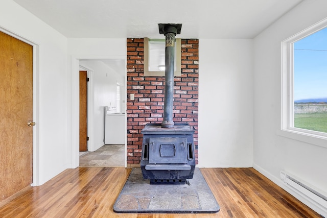 1680 W River Rd, Deer Lodge, MT 59722 - detailed view of a baseboard heating unit, a wood stove, wood finished floors, washer / dryer, and baseboards