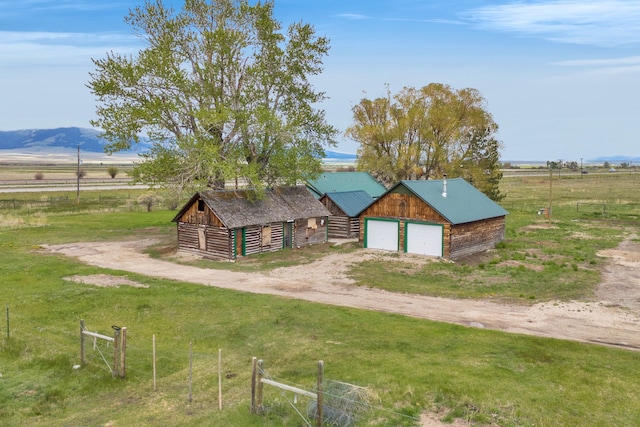 1680 W River Rd, Deer Lodge, MT 59722 - view of front of house with a detached garage, an outbuilding, a rural view, driveway, and metal roof