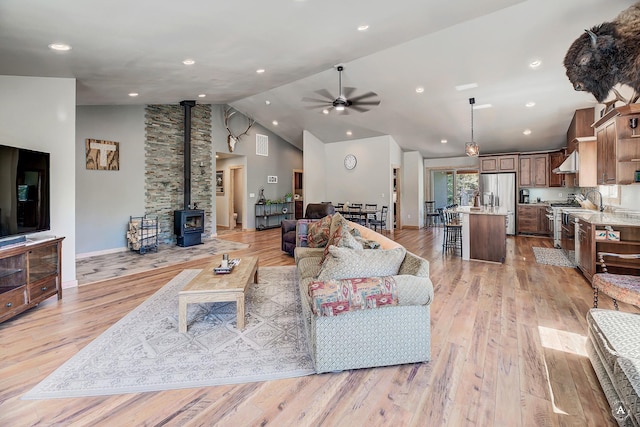 115 Grassy Mountain Rd, White Sulphur Springs, MT 59645 - living area with a wood stove, a ceiling fan, light wood-type flooring, baseboards, and high vaulted ceiling