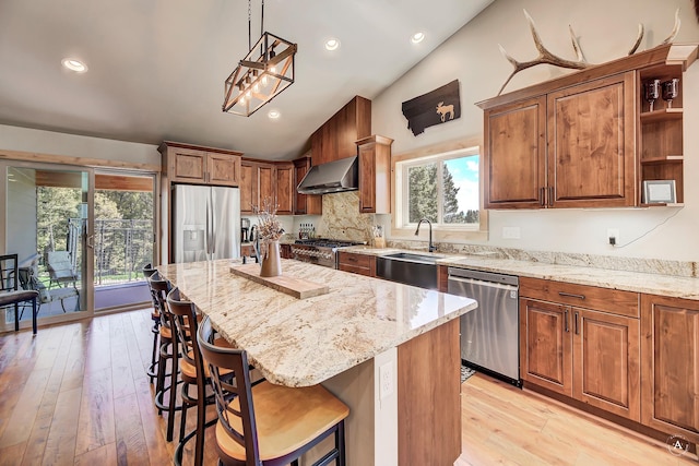 115 Grassy Mountain Rd, White Sulphur Springs, MT 59645 - kitchen featuring appliances with stainless steel finishes, vaulted ceiling, wall chimney range hood, light stone counters, and a kitchen bar