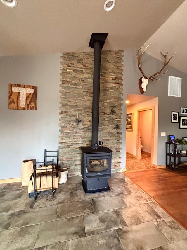 115 Grassy Mountain Rd, White Sulphur Springs, MT 59645 - living area with vaulted ceiling, a wood stove, stone finish flooring, and baseboards