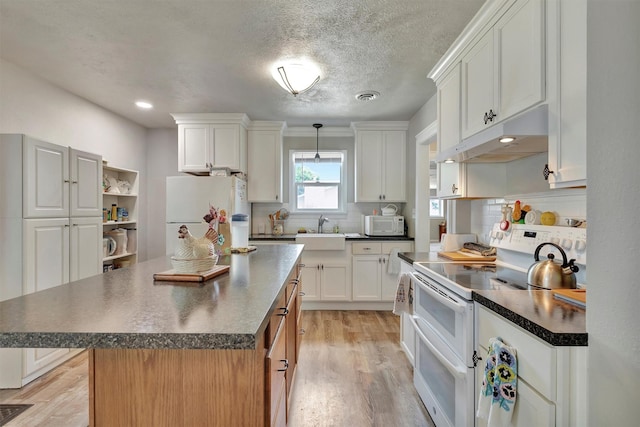 510 Mission St, Stevensville, MT 59870 - kitchen with white appliances, under cabinet range hood, dark countertops, decorative backsplash, and a textured ceiling