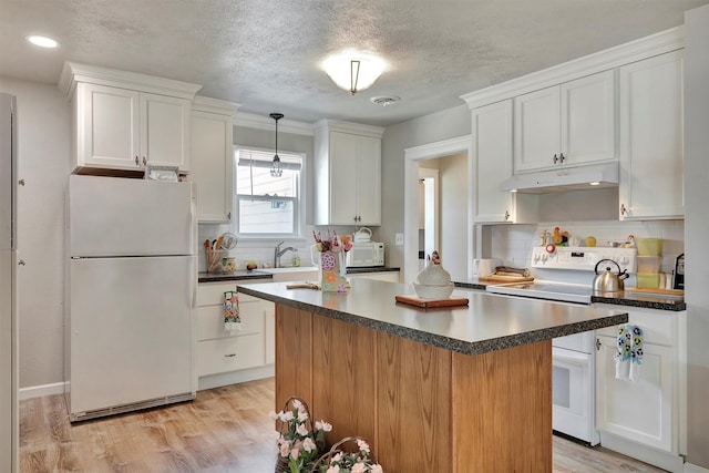 510 Mission St, Stevensville, MT 59870 - kitchen with white appliances, under cabinet range hood, dark countertops, white cabinetry, and tasteful backsplash