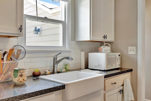 510 Mission St, Stevensville, MT 59870 - kitchen featuring white microwave, a sink, decorative backsplash, and dark countertops