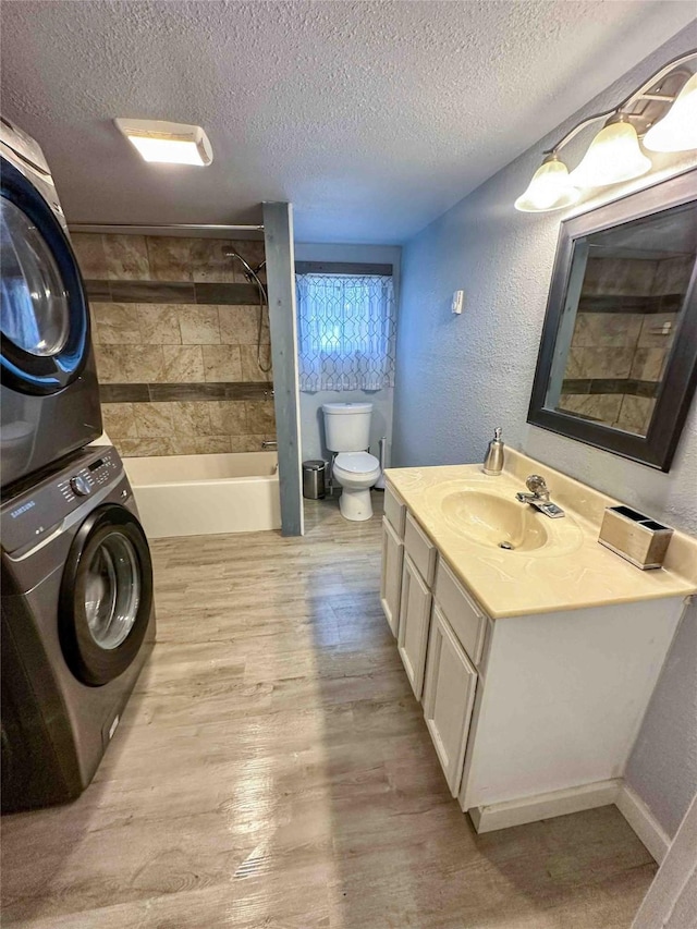 210 S Maryland St, Conrad, MT 59425 - full bathroom featuring stacked washer / dryer, toilet, a textured ceiling, vanity, and wood finished floors