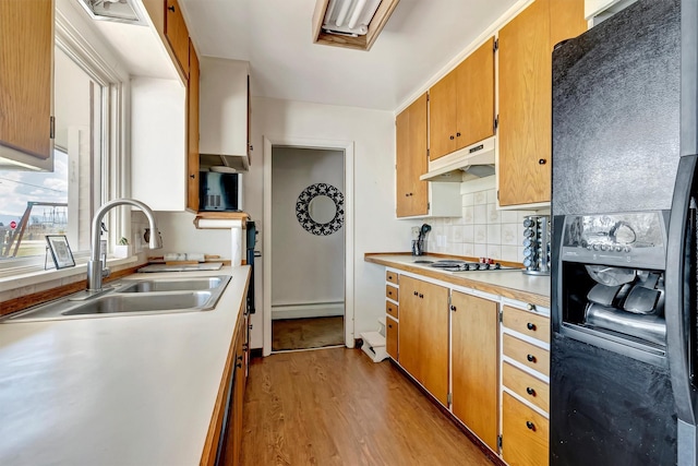 611 Old Corvallis Rd, Corvallis, MT 59828 - kitchen featuring black fridge, under cabinet range hood, baseboard heating, cooktop, and light wood finished floors