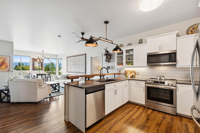 100 Woodlands Way Unit S305, Kalispell, MT 59901 - kitchen featuring appliances with stainless steel finishes, dark countertops, a peninsula, a chandelier, and tasteful backsplash