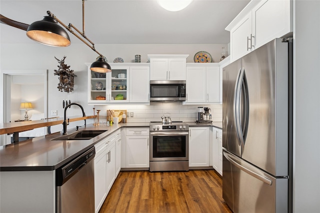 100 Woodlands Way Unit S305, Kalispell, MT 59901 - kitchen with stainless steel appliances, a peninsula, dark countertops, white cabinetry, and glass insert cabinets