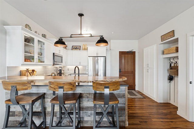 100 Woodlands Way Unit S305, Kalispell, MT 59901 - kitchen with appliances with stainless steel finishes, a peninsula, glass insert cabinets, backsplash, and white cabinets
