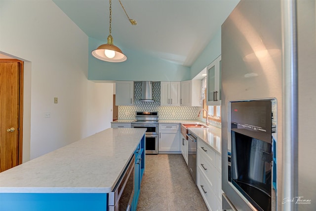 2685 Pinkerton Dr, East Helena, MT 59635 - kitchen with wall chimney range hood, stainless steel appliances, backsplash, vaulted ceiling, and white cabinets