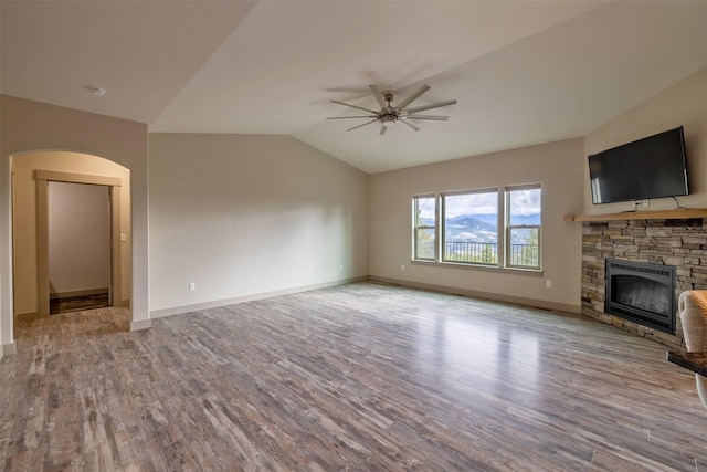 3525 Overland Rd, Helena, MT 59602 - unfurnished living room with a ceiling fan, a stone fireplace, arched walkways, lofted ceiling, and wood finished floors