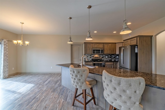 3525 Overland Rd, Helena, MT 59602 - kitchen featuring appliances with stainless steel finishes, a sink, tasteful backsplash, light wood finished floors, and a kitchen bar