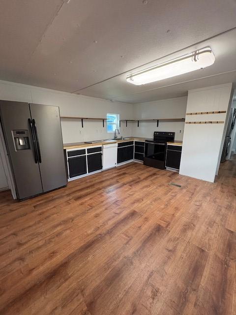 15291 Mullan Rd, Missoula, MT 59808 - kitchen featuring black range with electric stovetop, stainless steel fridge with ice dispenser, light wood-style floors, light countertops, and a sink