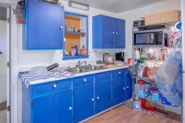 945 3rd Ave W, Kalispell, MT 59901 - kitchen with stainless steel microwave, blue cabinetry, light wood finished floors, light countertops, and open shelves