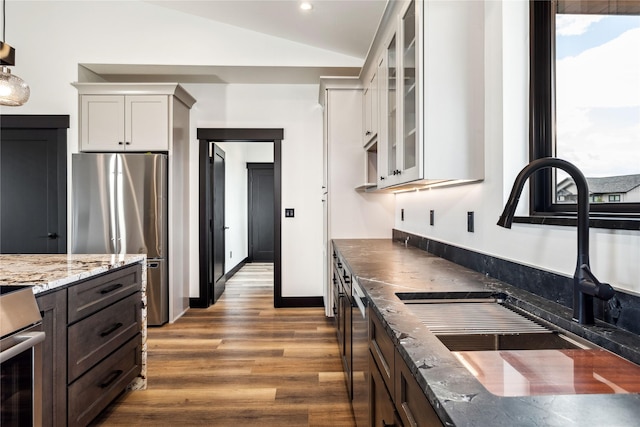 34544 Eagle Crest Dr, Polson, MT 59860 - kitchen with stainless steel appliances, a sink, light stone countertops, wood finished floors, and glass insert cabinets