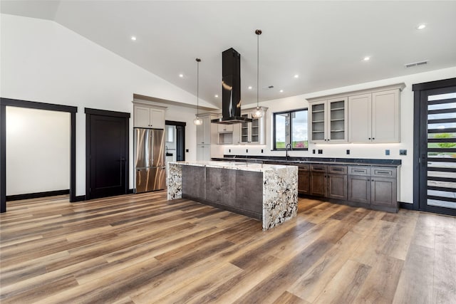 34544 Eagle Crest Dr, Polson, MT 59860 - kitchen featuring freestanding refrigerator, island exhaust hood, a center island, vaulted ceiling, and light wood-style floors