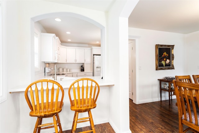 173 Empire Loop, Kalispell, MT 59901 - kitchen with white refrigerator with ice dispenser, arched walkways, a sink, dark wood-style floors, and light countertops