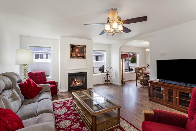 173 Empire Loop, Kalispell, MT 59901 - living area with arched walkways, a glass covered fireplace, ceiling fan, wood finished floors, and baseboards