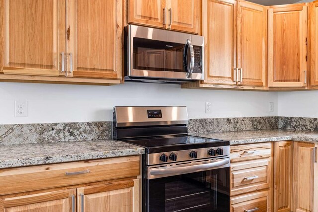 28 Mackenzie Mountain Way, Three Forks, MT 59752 - kitchen featuring appliances with stainless steel finishes, light stone counters, and light brown cabinetry