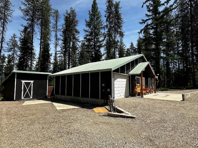 194 Whitetail Dr, Haugan, MT 59842 - view of outbuilding with gravel driveway and a sunroom