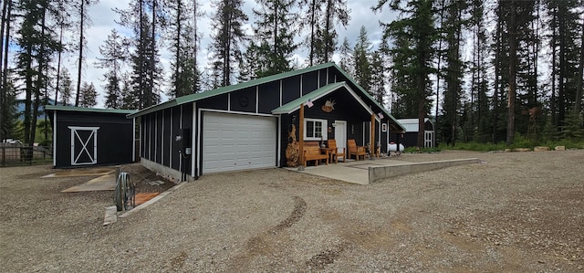 194 Whitetail Dr, Haugan, MT 59842 - view of front facade with an attached garage, board and batten siding, an outdoor structure, and dirt driveway