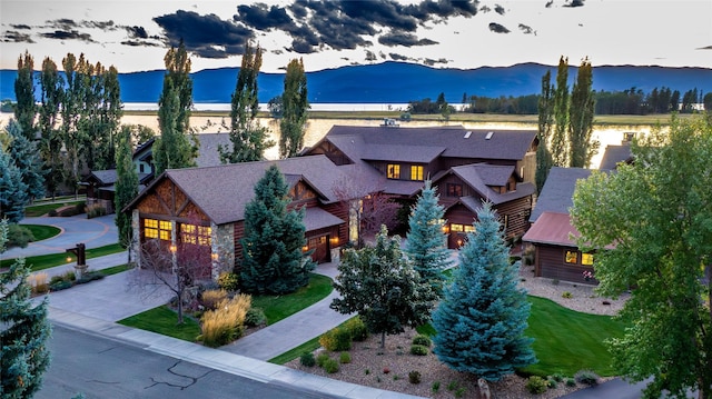 237 Harbor Dr, Bigfork, MT 59911 - view of front facade featuring a mountain view, driveway, stone siding, and a shingled roof