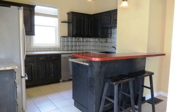 726 4th Ave S, Great Falls, MT 59405 - kitchen with stainless steel dishwasher, freestanding refrigerator, a breakfast bar, decorative backsplash, and a sink
