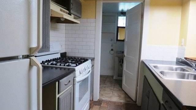 726 4th Ave S, Great Falls, MT 59405 - kitchen with white appliances, a sink, tasteful backsplash, and under cabinet range hood