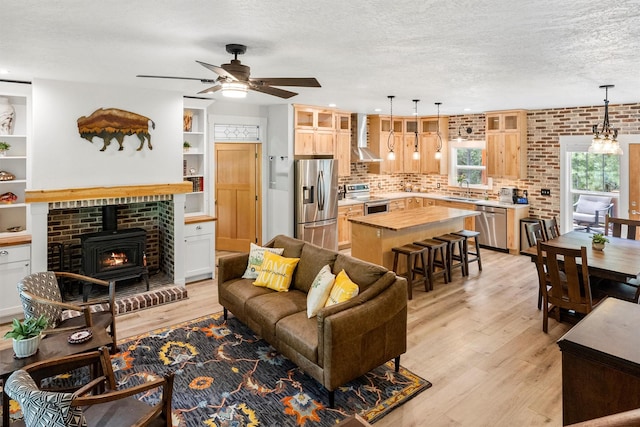 11501 Sleeman Creek Rd, Lolo, MT 59847 - living room featuring a wood stove, light wood-style floors, a ceiling fan, and a textured ceiling