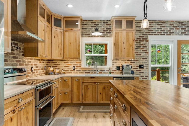 11501 Sleeman Creek Rd, Lolo, MT 59847 - kitchen with double oven range, wall chimney range hood, butcher block countertops, light wood finished floors, and decorative light fixtures
