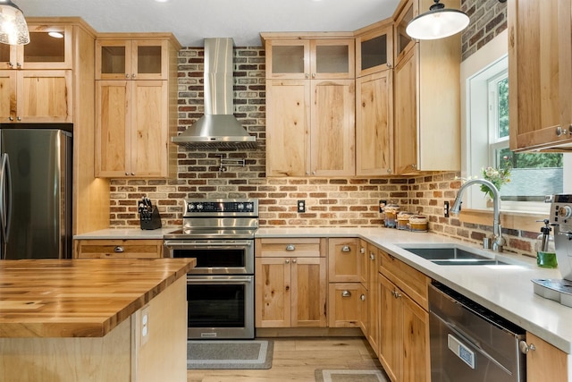 11501 Sleeman Creek Rd, Lolo, MT 59847 - kitchen featuring appliances with stainless steel finishes, wall chimney range hood, wooden counters, light wood-style floors, and decorative light fixtures