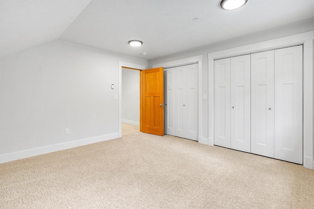 11501 Sleeman Creek Rd, Lolo, MT 59847 - unfurnished bedroom featuring multiple closets, light carpet, and vaulted ceiling