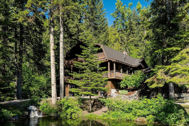 151 Handkerchief Creek Dr, Kalispell, MT 59901 - rear view of house with a gambrel roof, a wooded view, and a balcony