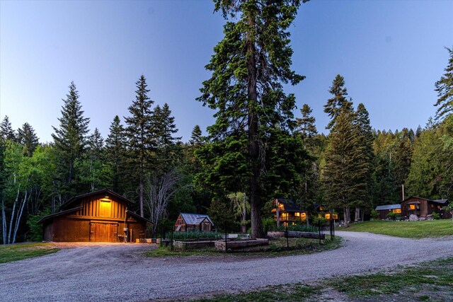 151 Handkerchief Creek Dr, Kalispell, MT 59901 - view of front of house with a wooded view, a detached garage, and a barn